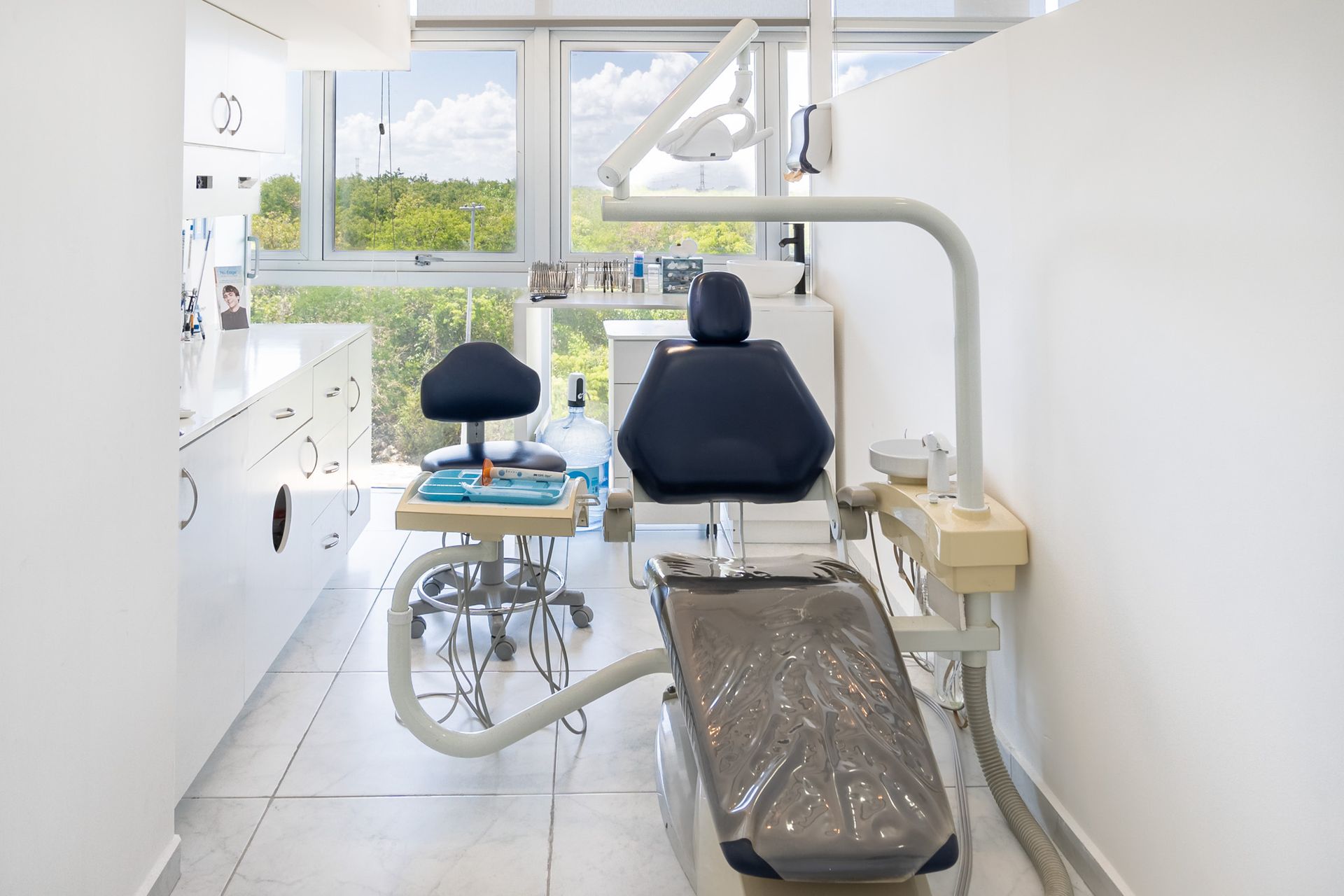 Sillón de exploración dental en una clínica luminosa con ventana y equipo incorporado.