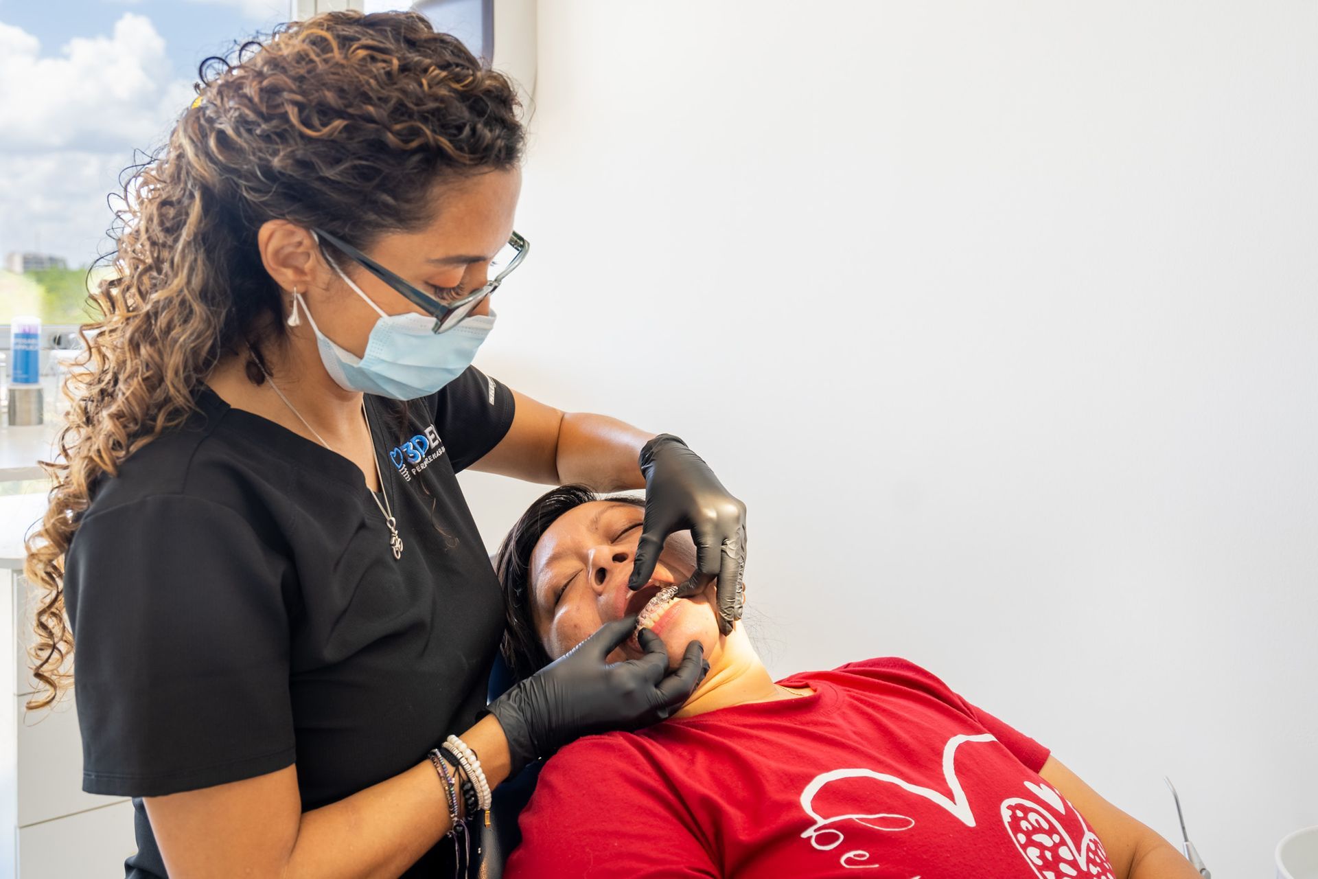 Odontólogo examinando la boca de un paciente con instrumental dental mientras usa mascarilla y guantes.