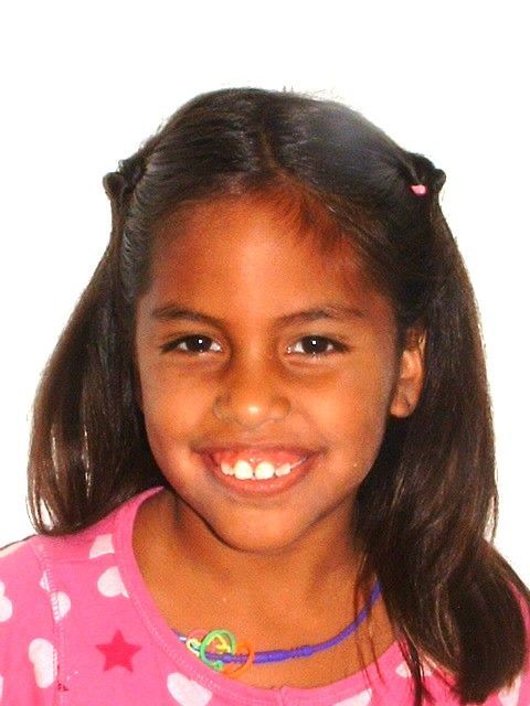 Niña sonriente con una camisa rosa con estampado de estrellas, sobre un fondo blanco liso.