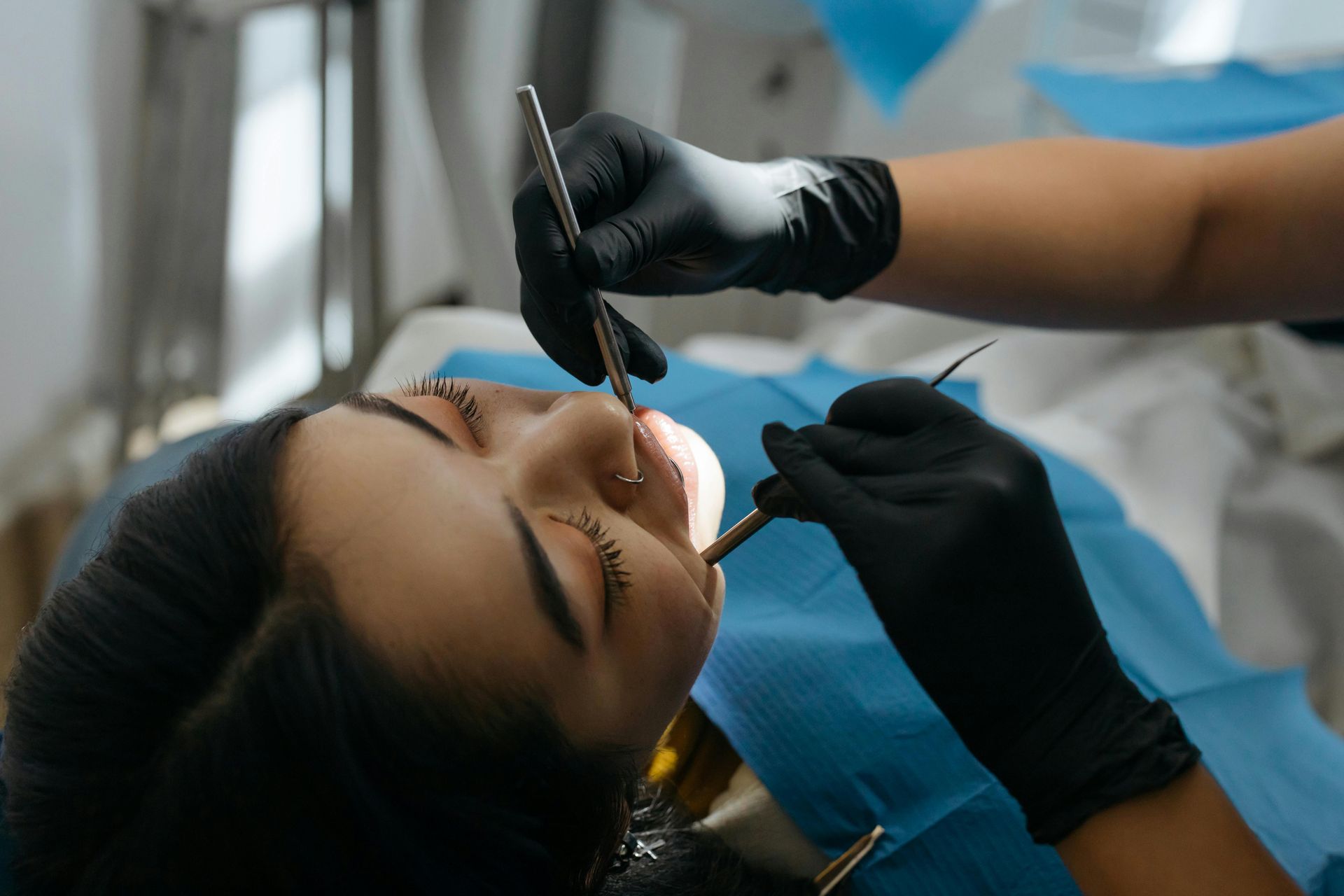 Dentista con guantes trabajando en los dientes de un paciente en el sillón dental.