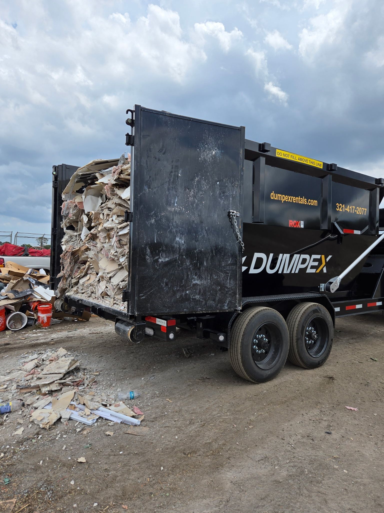 Home renovation debris sorted beside a roll-off dumpster