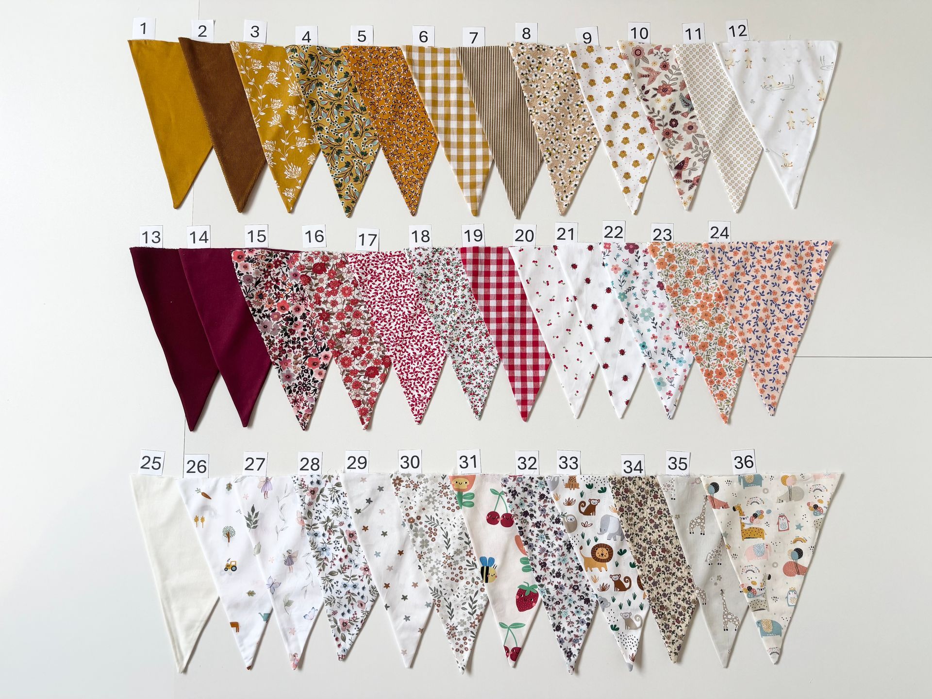 Rijen genummerde decoratieve vlaggetjes in goud-, roze- en witte patronen op een witte muur.