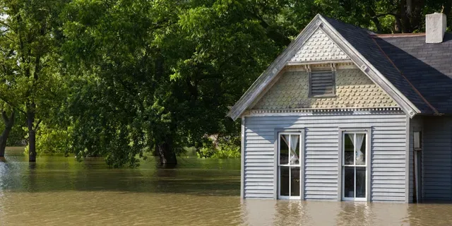 A house is sitting in the middle of a flooded area.