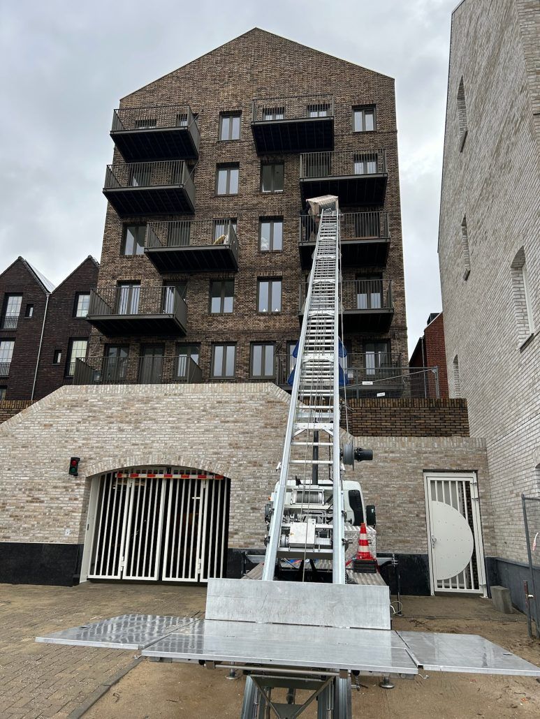 Een groot bakstenen gebouw met een ladder ervoor.