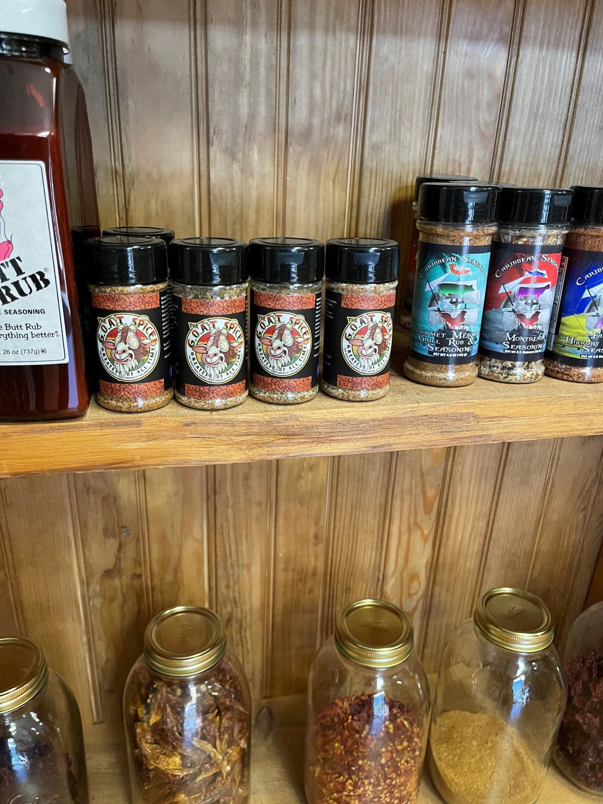 Spice jars and bottles arranged on wooden shelves against a wood-paneled wall.