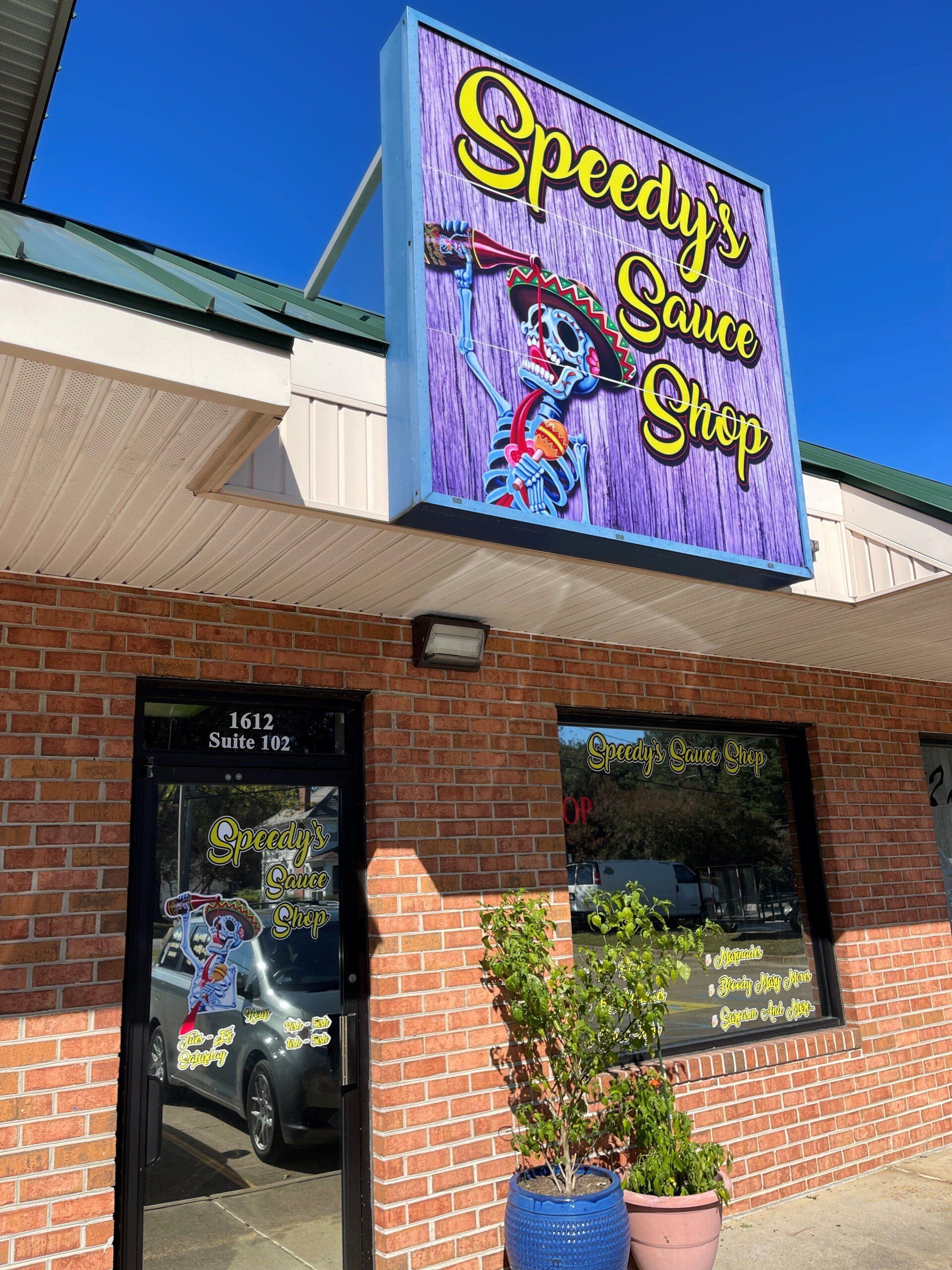 Speedy’s Sauce Shop storefront with colorful sign above a brick building and large windows