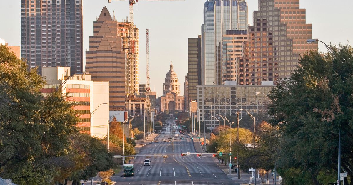 Austin, Texas skyline at dusk, with buildings of various heights and a bridge over a river.