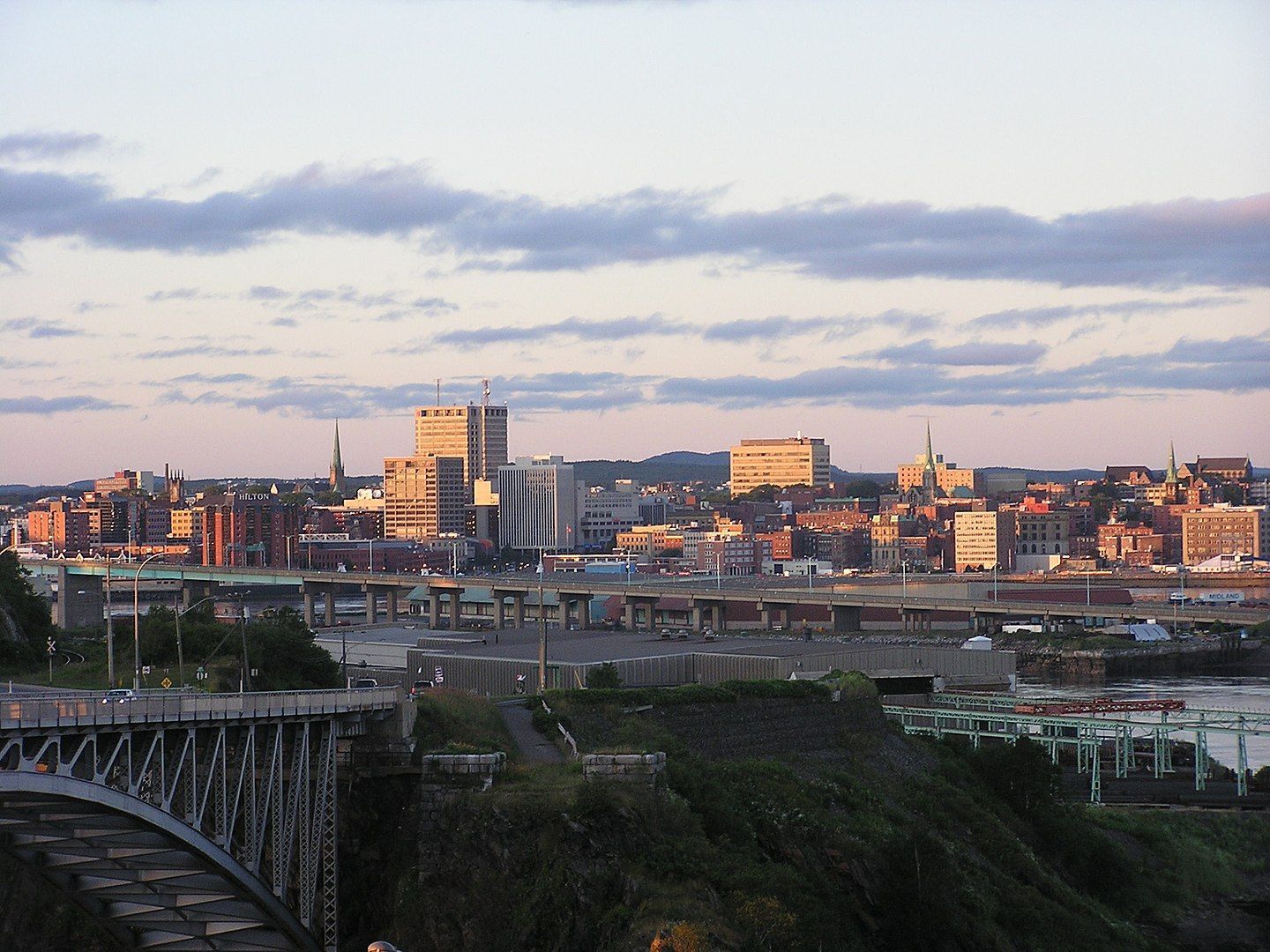 Saint John City skyline at sunset with buildings and bridges.