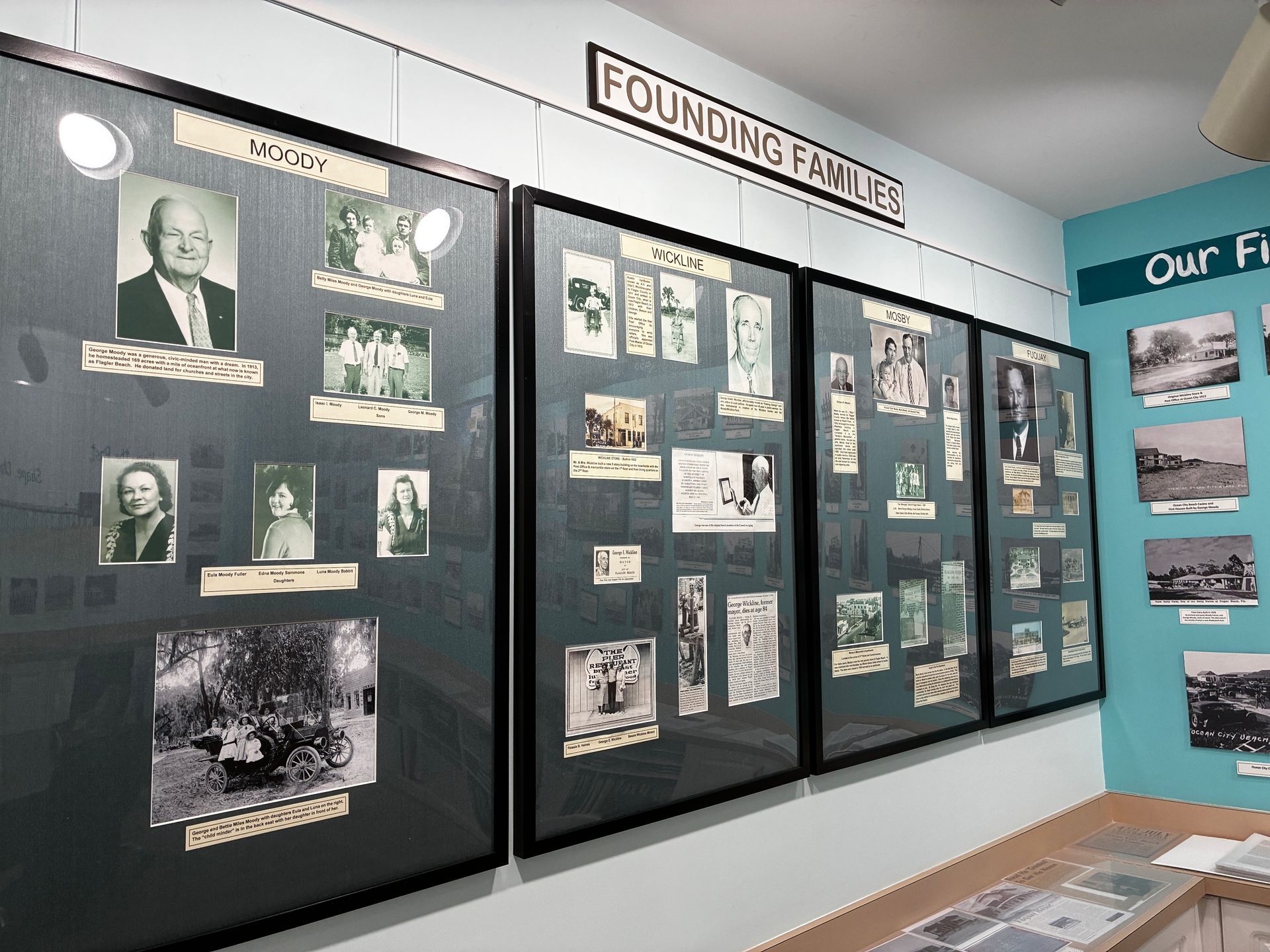 Museum hallway with black-framed history display boards and a “Founding Hive” sign above them