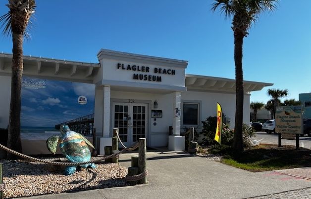Flagler Beach Museum entrance with palm trees, beach mural, and whale sculpture outside