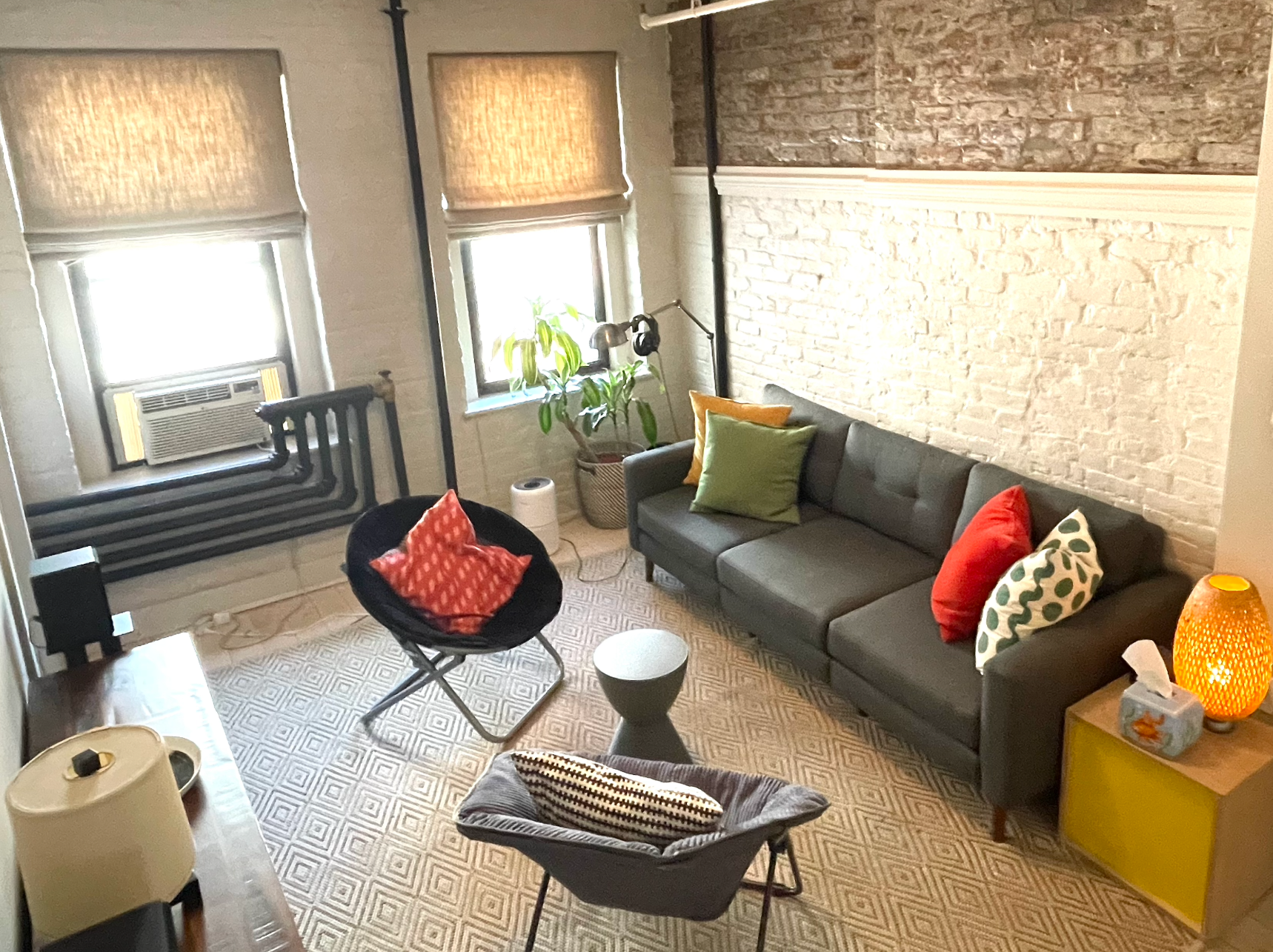 A living room with a couch and chairs and a brick wall.
