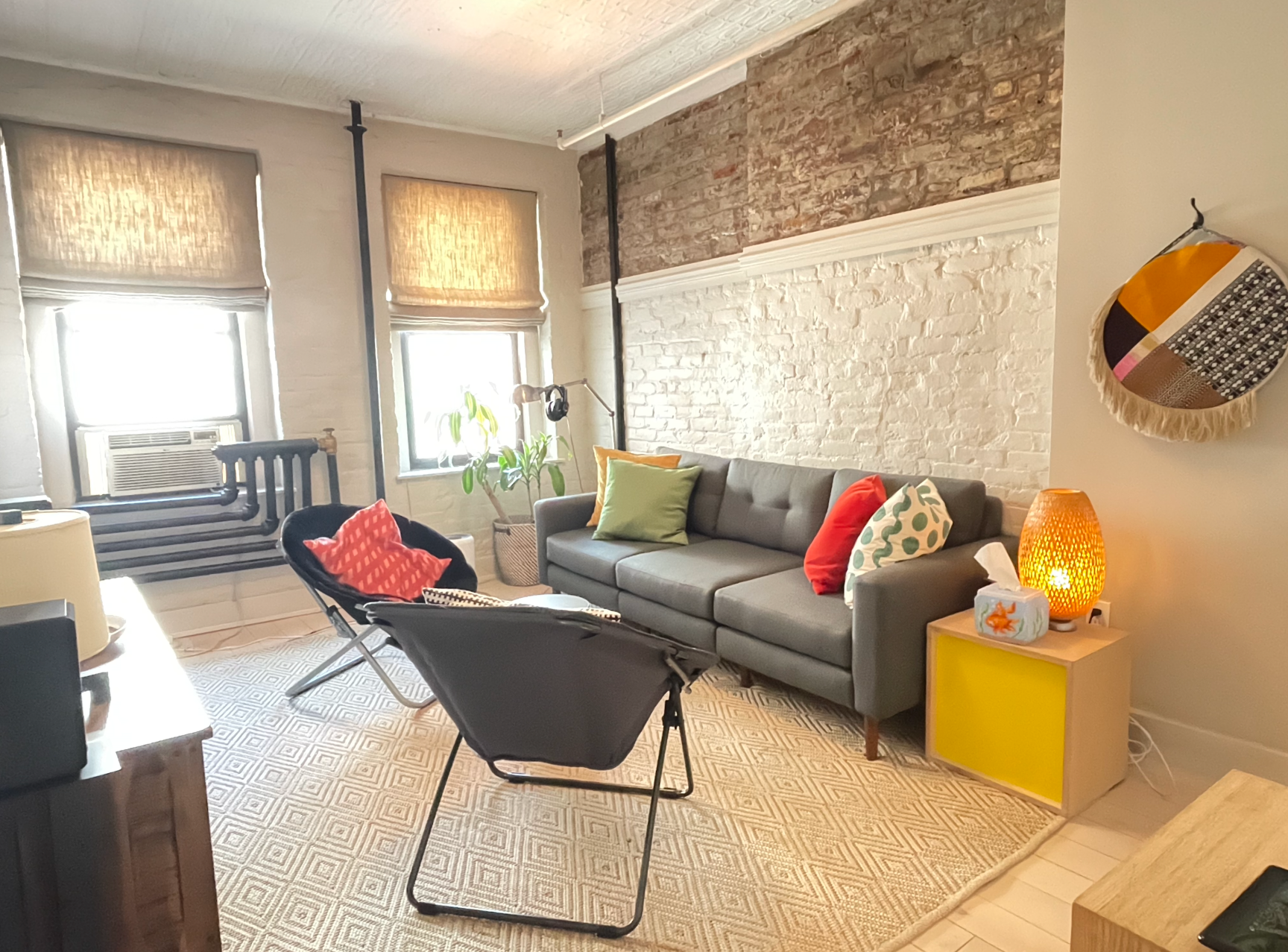 A living room with a couch and chairs and a brick wall.