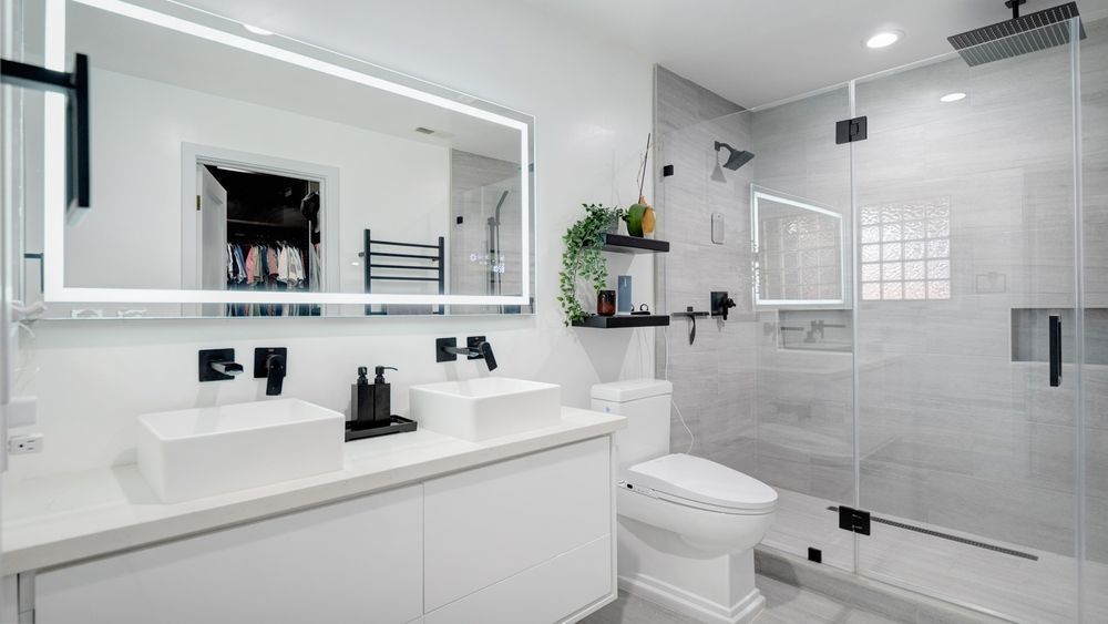 A bathroom with two sinks , a toilet , and a walk in shower.