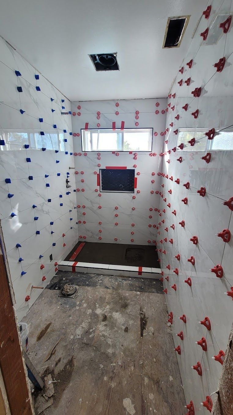 A bathroom under construction with tiles on the walls and floor.