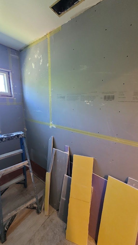 A room with a ladder and a bunch of boards on the floor.