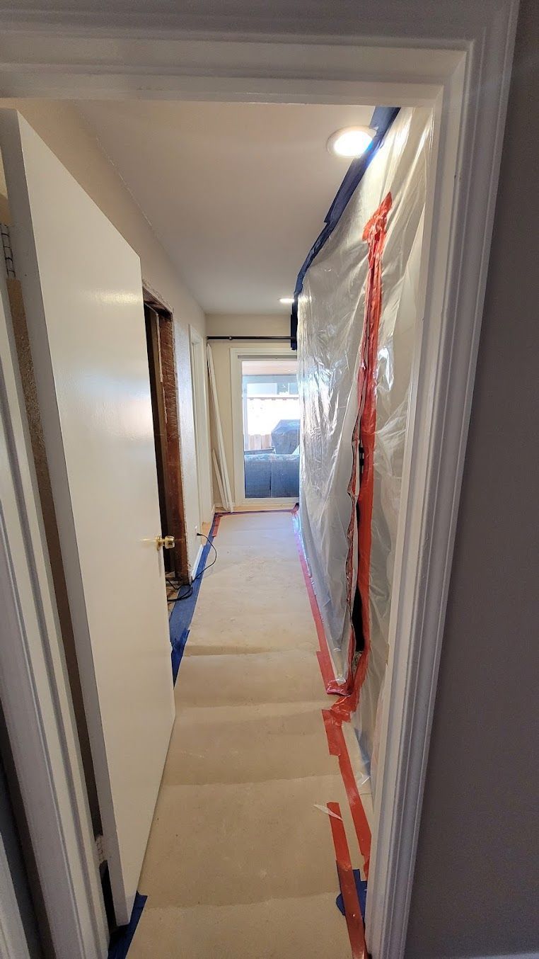 A long hallway covered in plastic and tape.