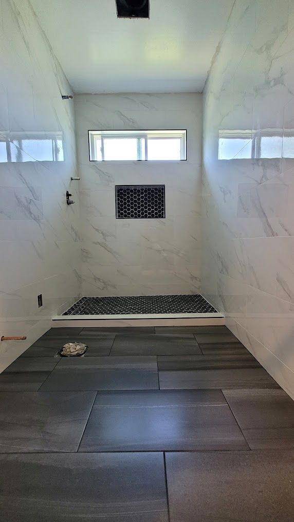 A bathroom with a walk in shower and a window.