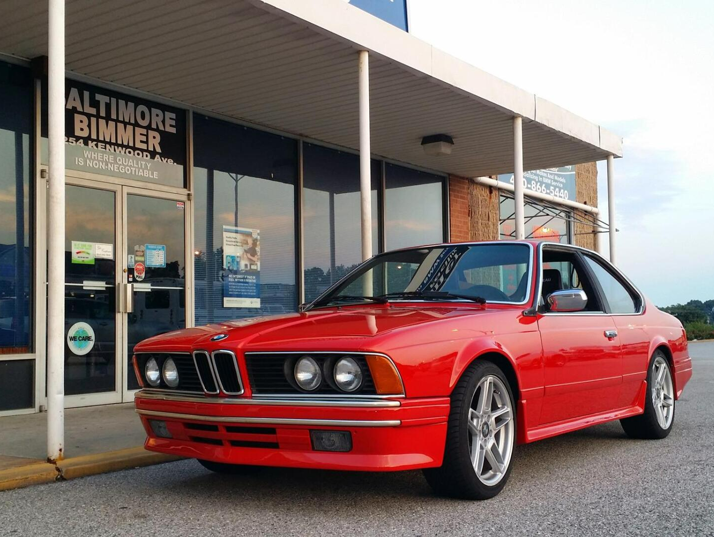 Red BMW coupe parked outside a Baltimore Bimmer dealership