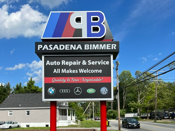 Pasadena Bimmer auto repair sign with red, blue, and black logo against a blue sky
