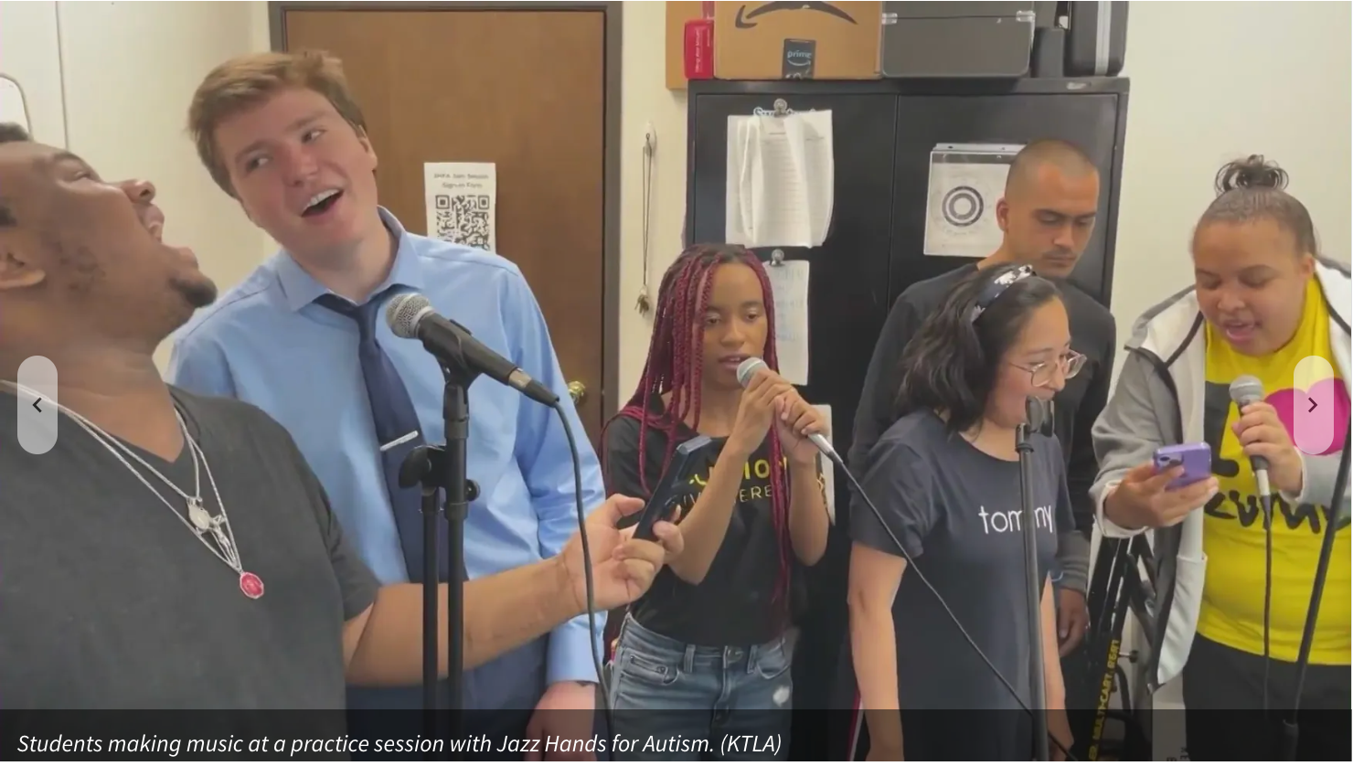 Group of people singing into microphones, smiling and laughing in a room.