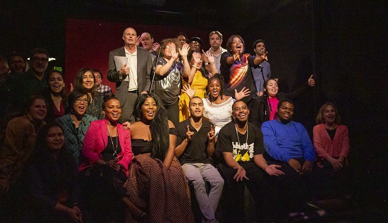 Group of people smiling and cheering in a dimly lit theater.