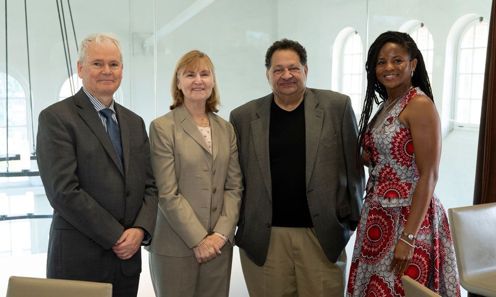 Four people posing indoors: two men and two women, smiling, in business attire.
