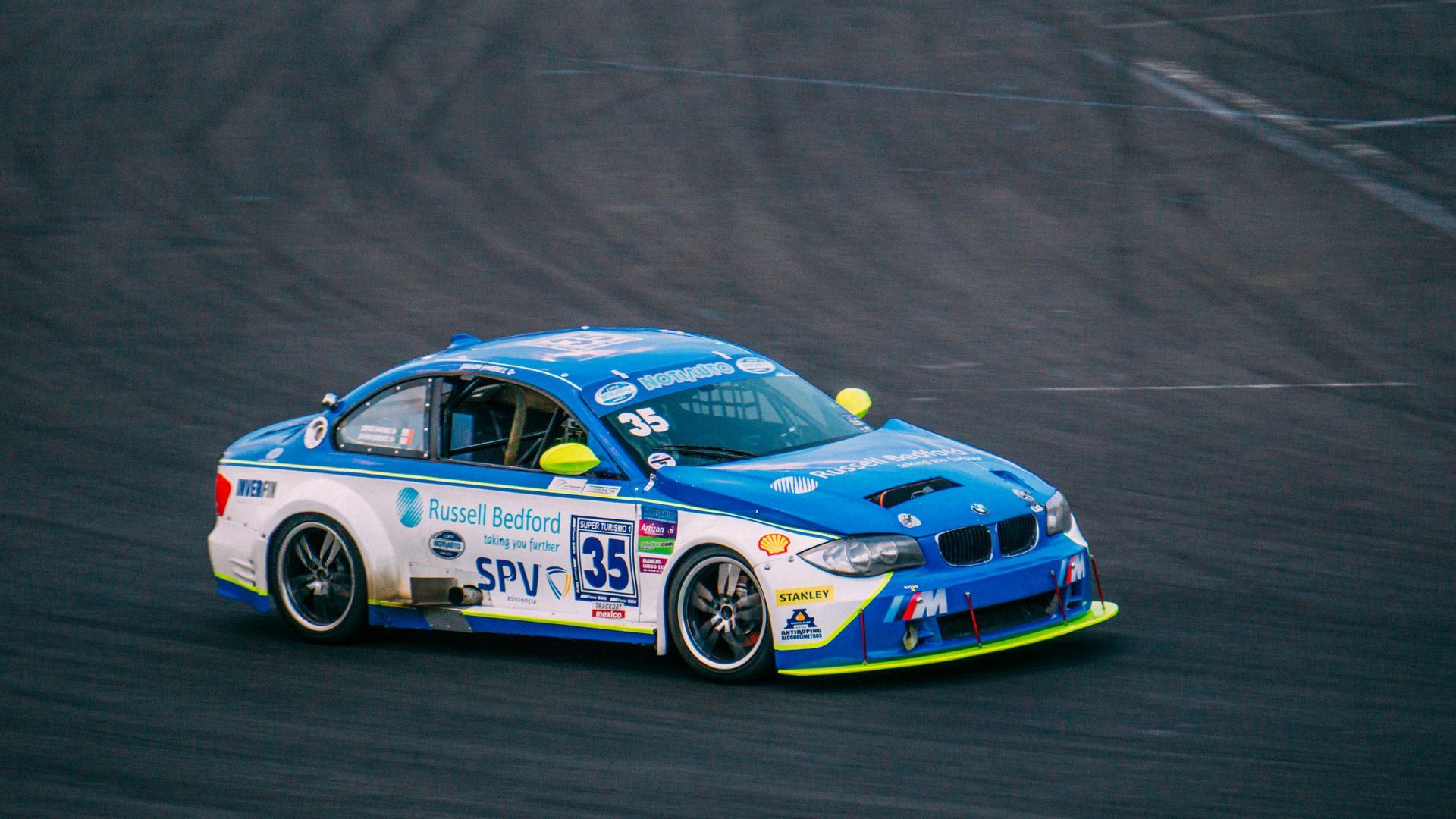 Blue-and-white race car speeding on a track, with sponsor decals and number 35 visible