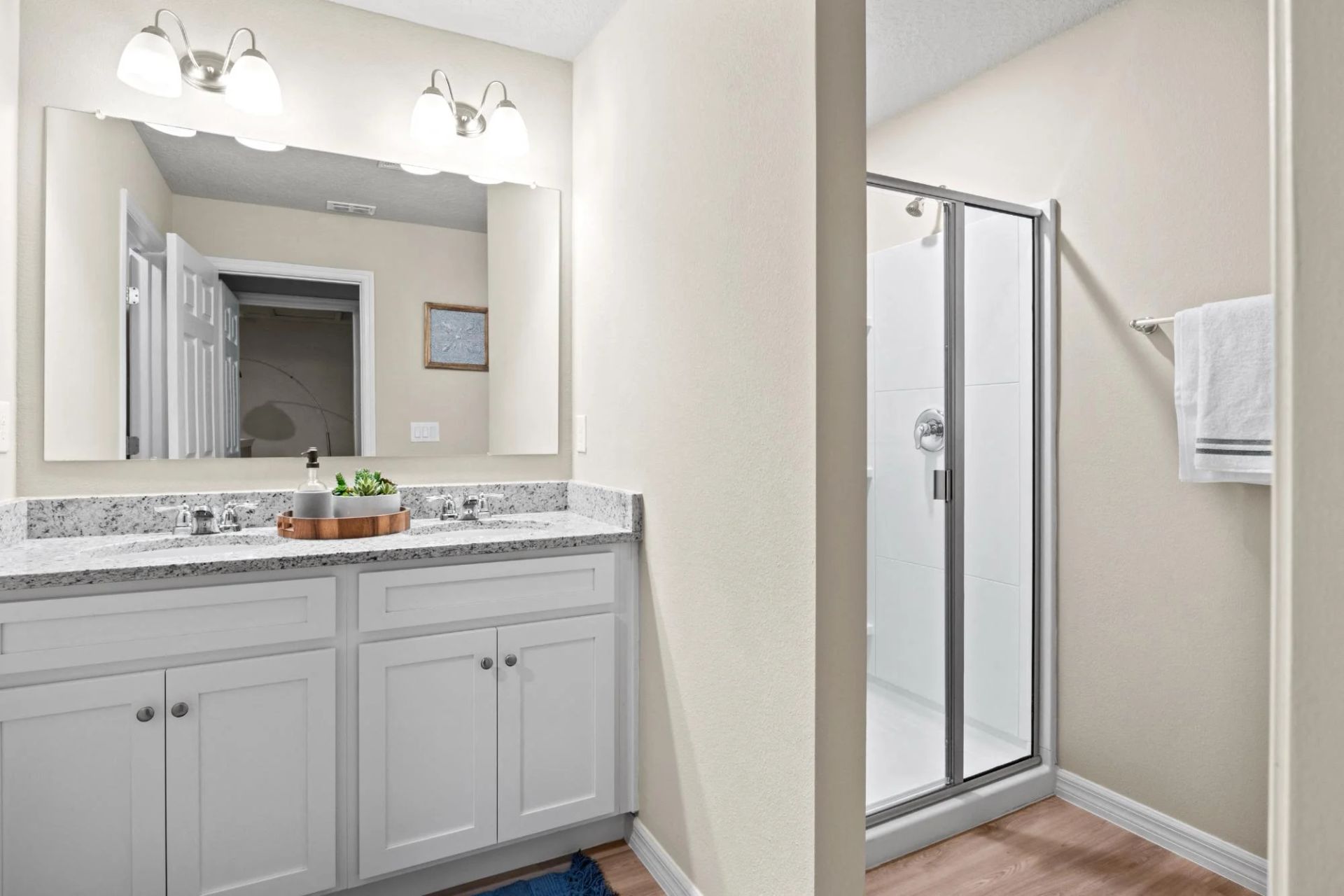 A bathroom with a double sink and a walk in shower.