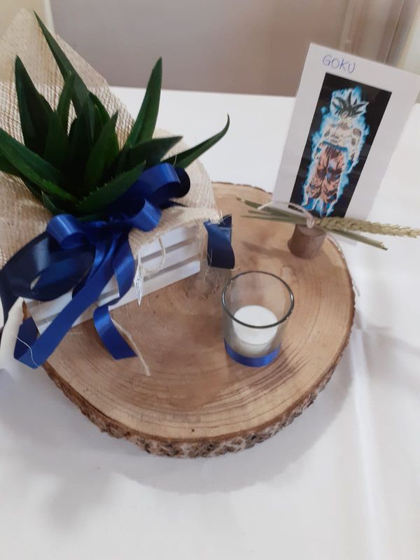 Centrotavola in legno con aloe vera, una candela, un'immagine di Goku e un nastro blu.