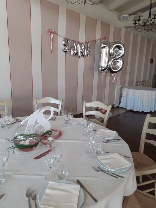 Tavolo apparecchiato per una festa, con palloncini che compongono la scritta