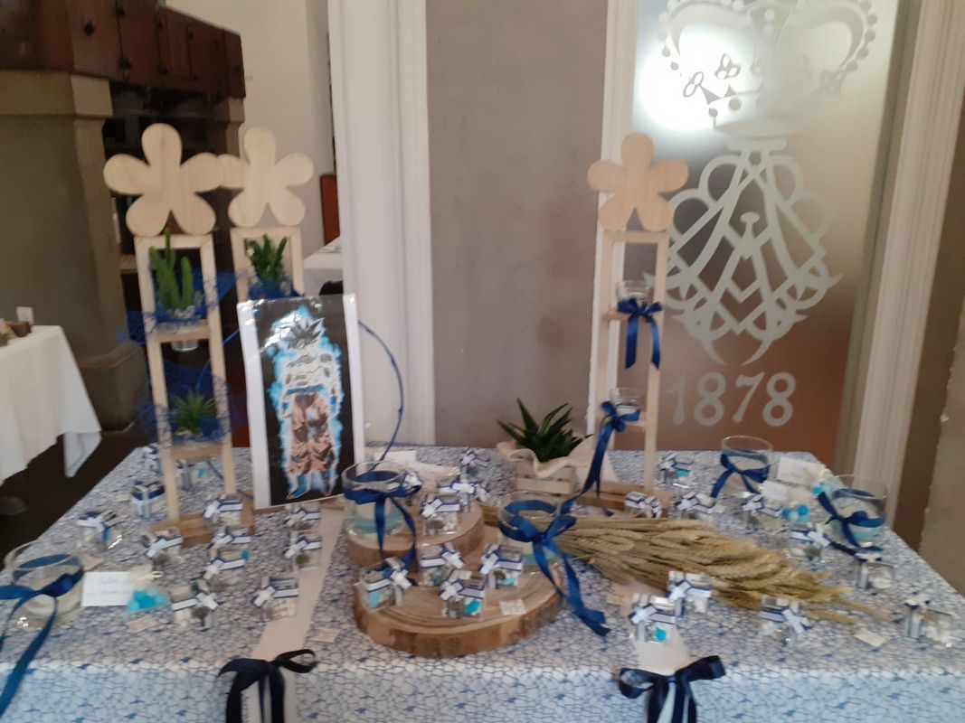 Tavolo decorato con bomboniere blu e bianche, dettagli in legno e decorazioni floreali.
