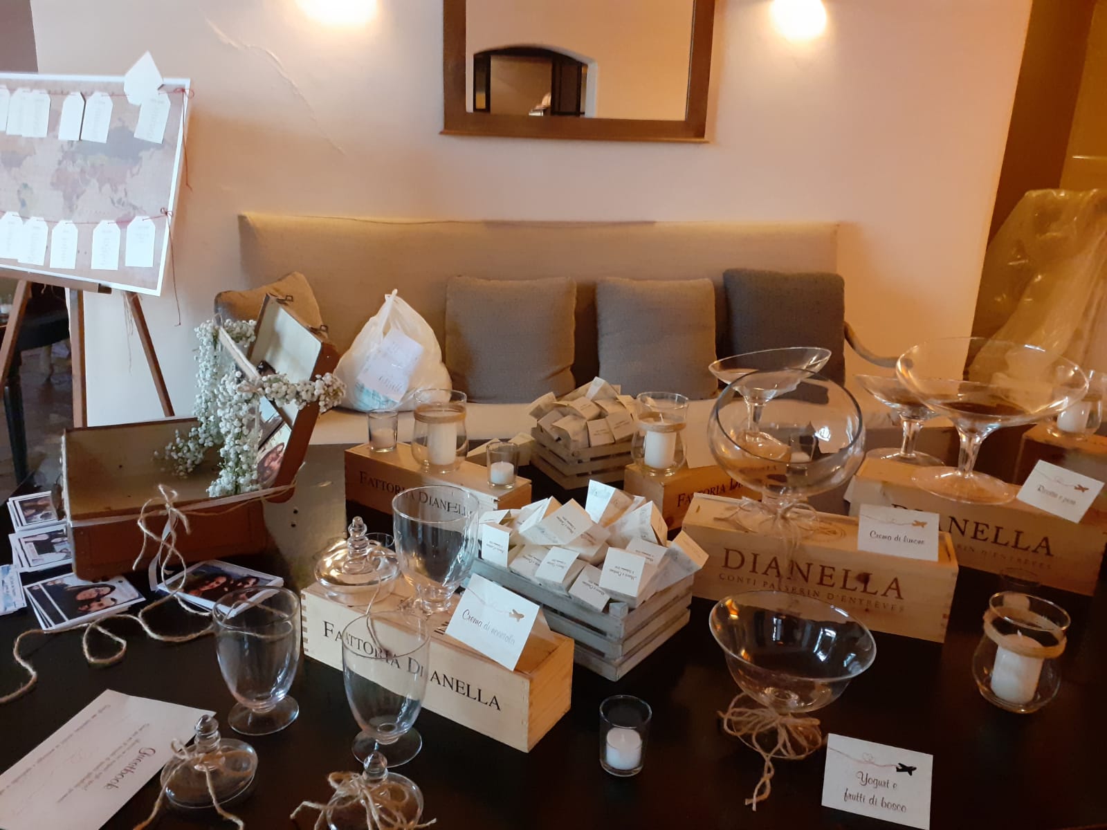 Tavolo del ricevimento nuziale con regali, decorazioni e scatole di vino.