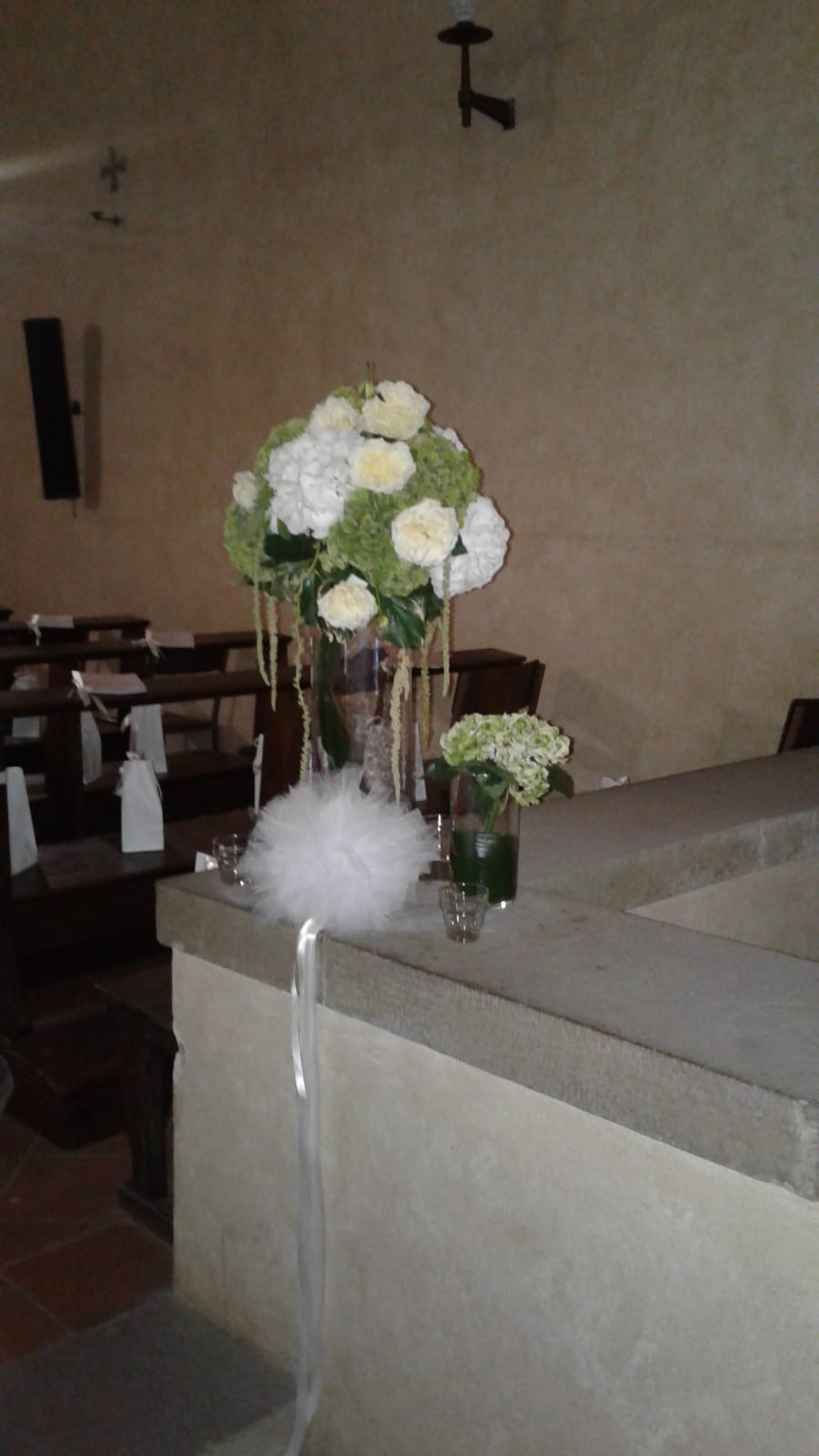 Composizioni floreali su una superficie in pietra in una chiesa. Grande bouquet, piccolo vaso e decorazioni bianche.