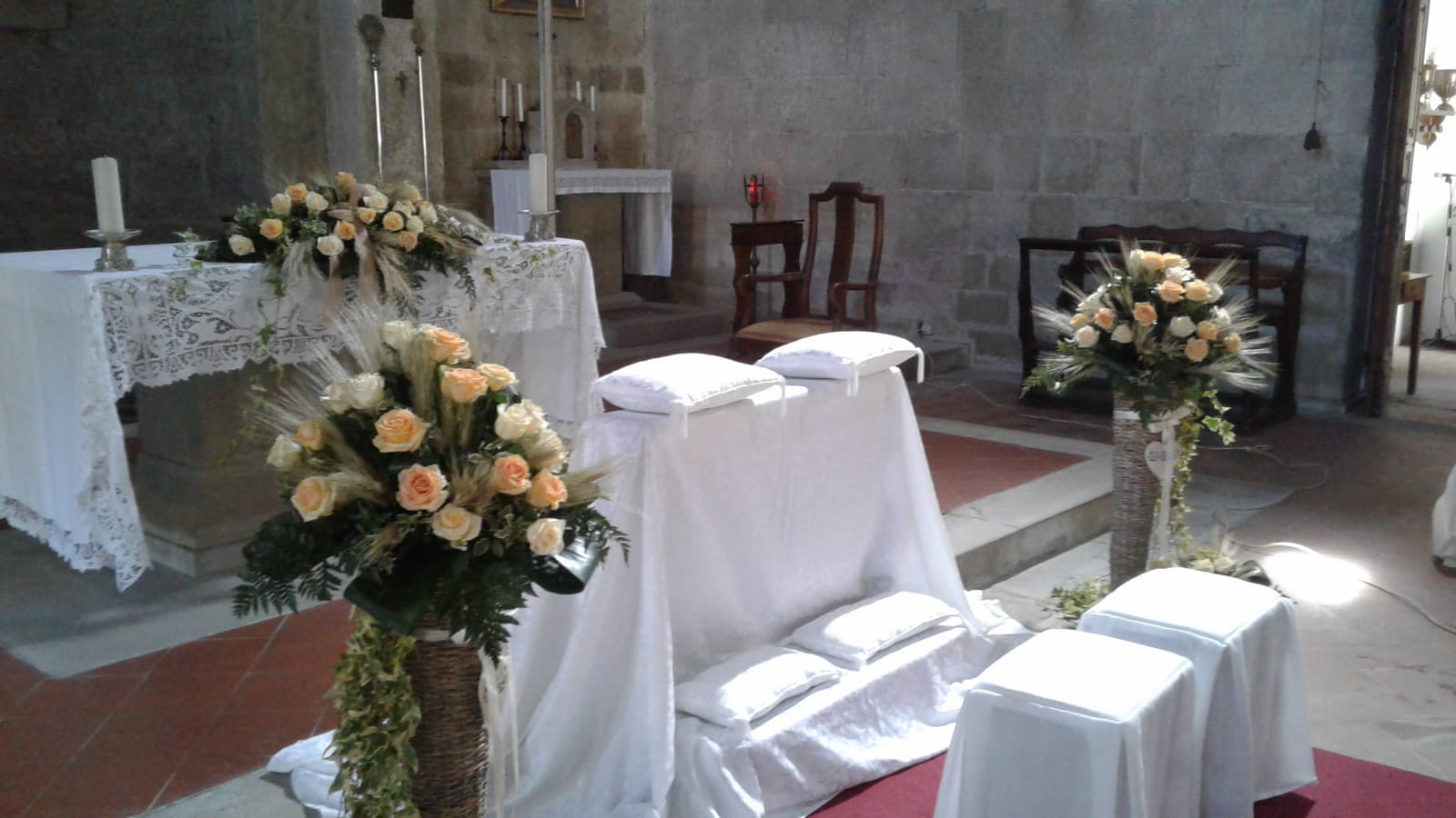 Cerimonia nuziale in chiesa, decorata con composizioni floreali bianche e gialle.