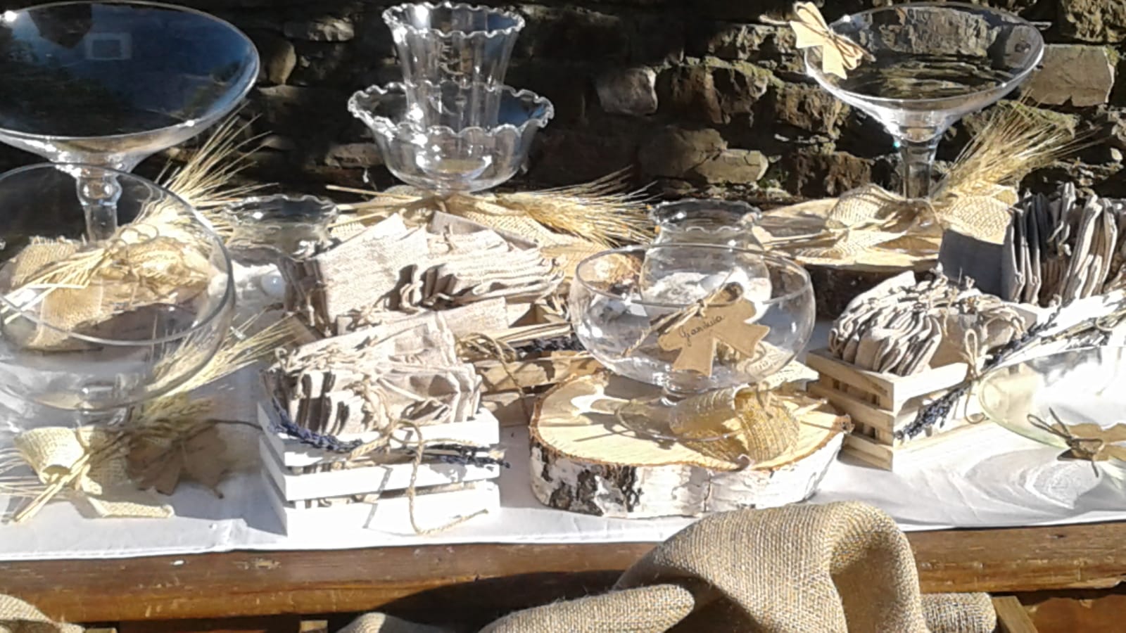 Apparecchiatura della tavola con vasi di vetro, decorazioni in legno e tela di iuta su uno sfondo di pietra.
