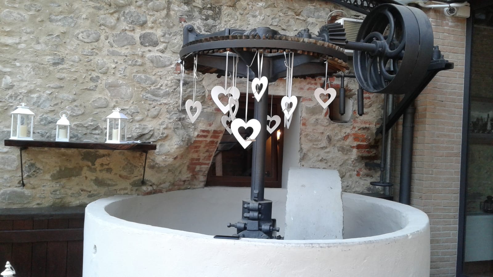 Vecchio pozzo con decorazioni a forma di cuore appese di fronte a un muro di pietra.
