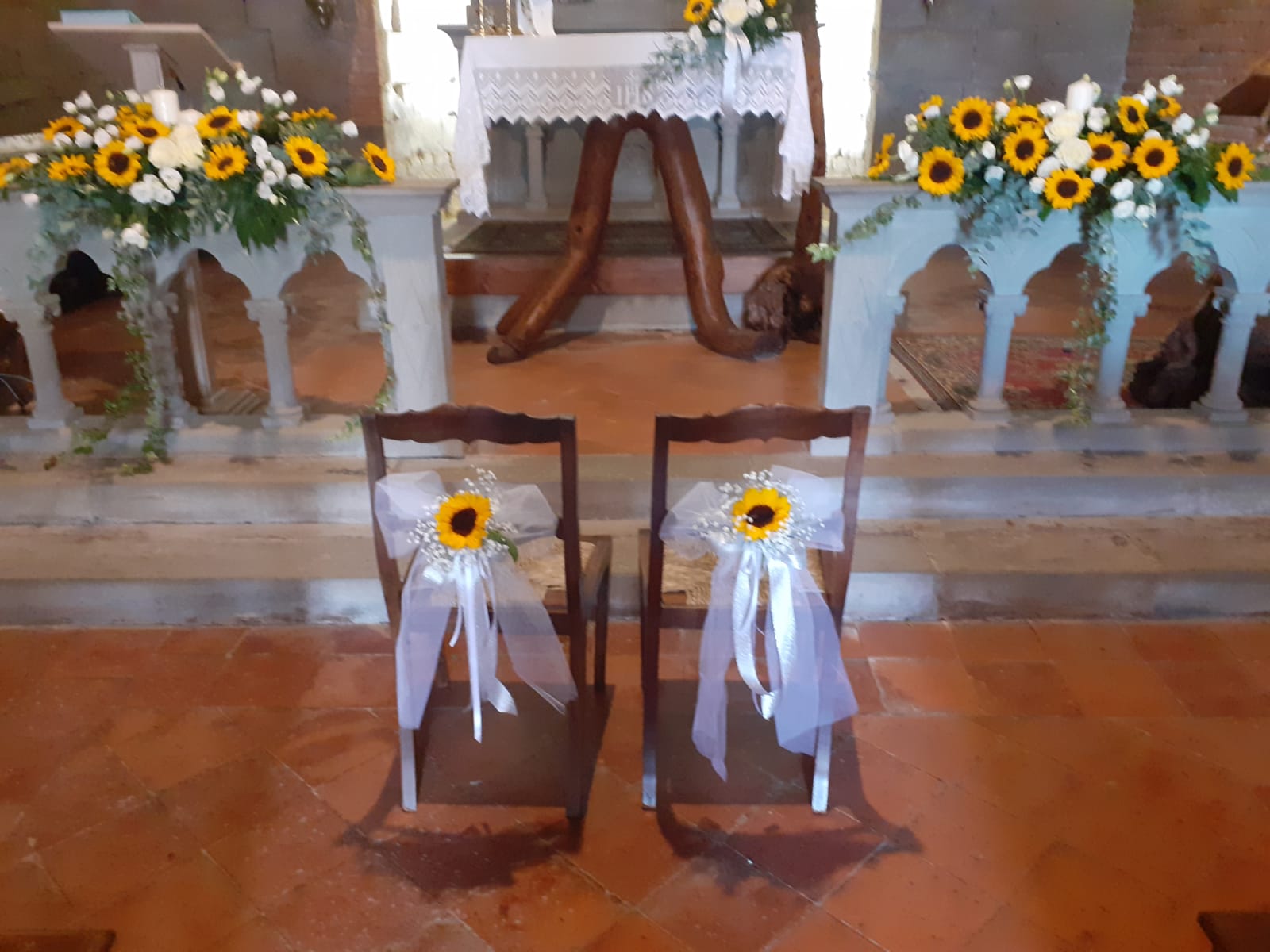 Due sedie decorate con girasoli e nastri sull'altare nuziale.