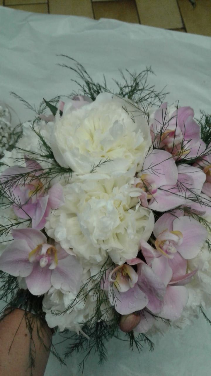 Bouquet di peonie bianche e orchidee viola chiaro con fogliame verde.
