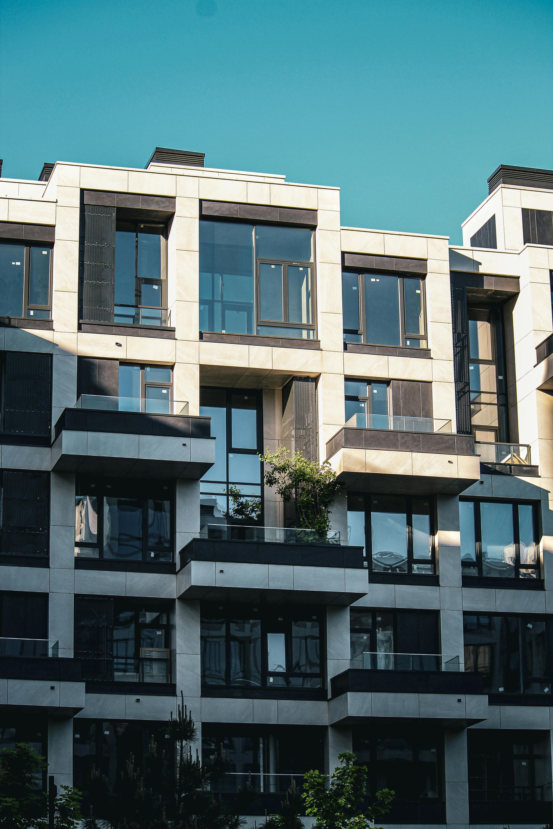 Modern white apartment building with large windows under a clear blue sky