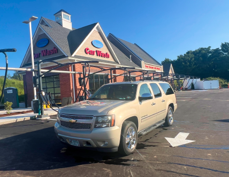 A silver suv is parked in front of a car wash.