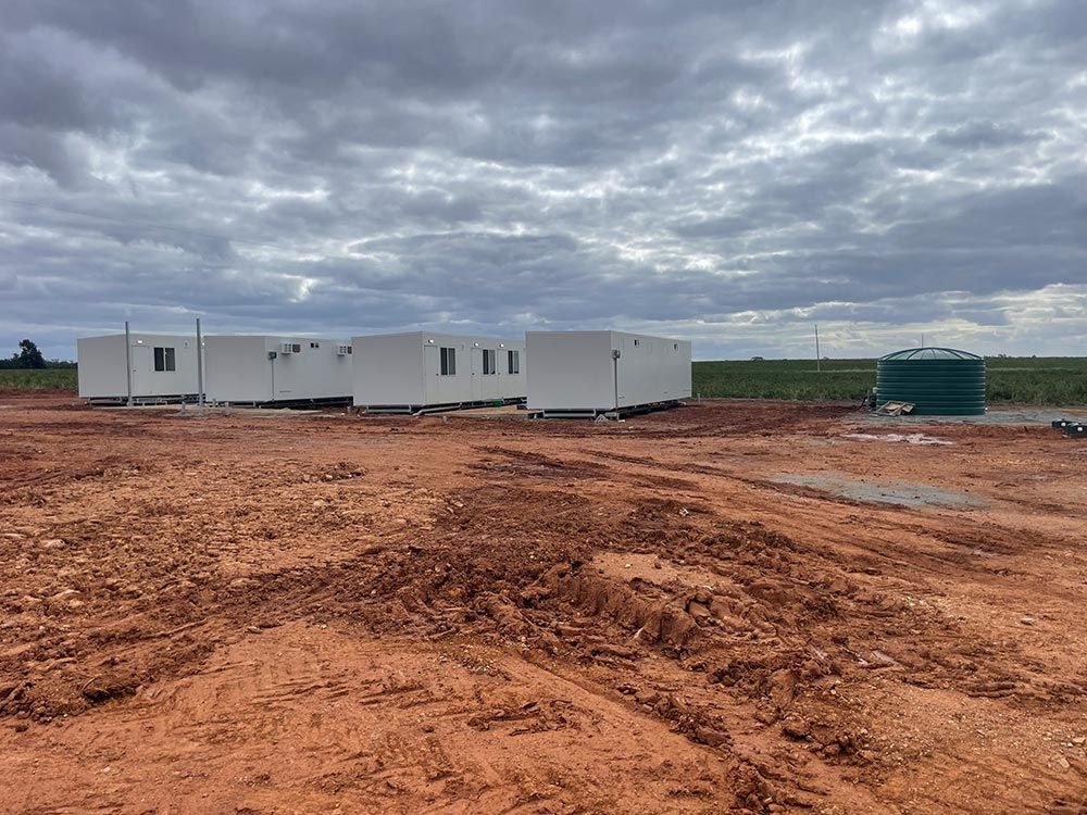 A row of White Buildings are Sitting in the Middle of a dirt Field — Pertzels Plumbing In Wagga Wagga, NSW