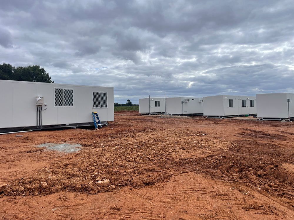 A Group Of White Buildings Are Sitting On Top Of A Dirt Field — Pertzels Plumbing In Wagga Wagga, NSW