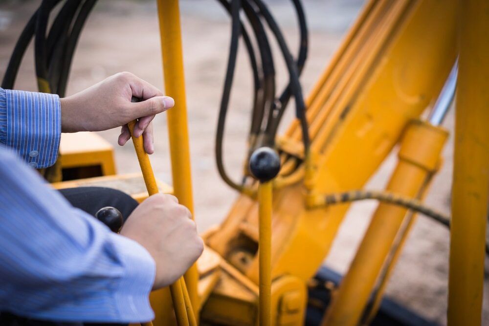 A Person Is Driving A Yellow Excavator On A Construction Site — Wilsons Excavations & Plant Hire in Byron Bay, NSW