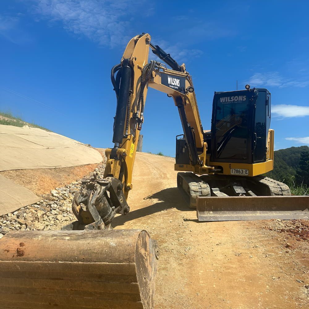 A Yellow Excavator With The Word Wilsons On The Front — Wilsons Excavations & Plant Hire in Byron Bay, NSW