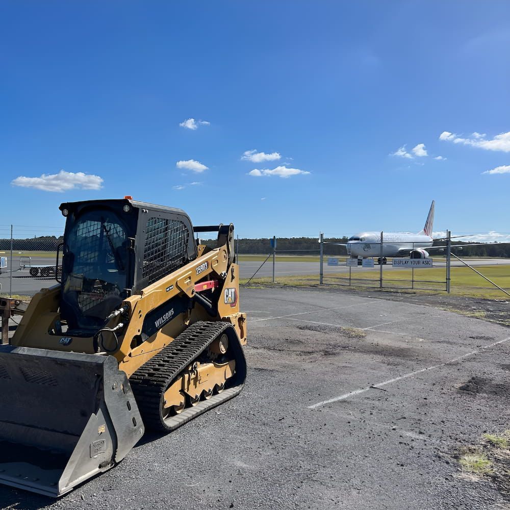A Bulldozer Is Parked In A Parking Lot With An Airplane — Wilsons Excavations & Plant Hire in Kingscliff, NSW