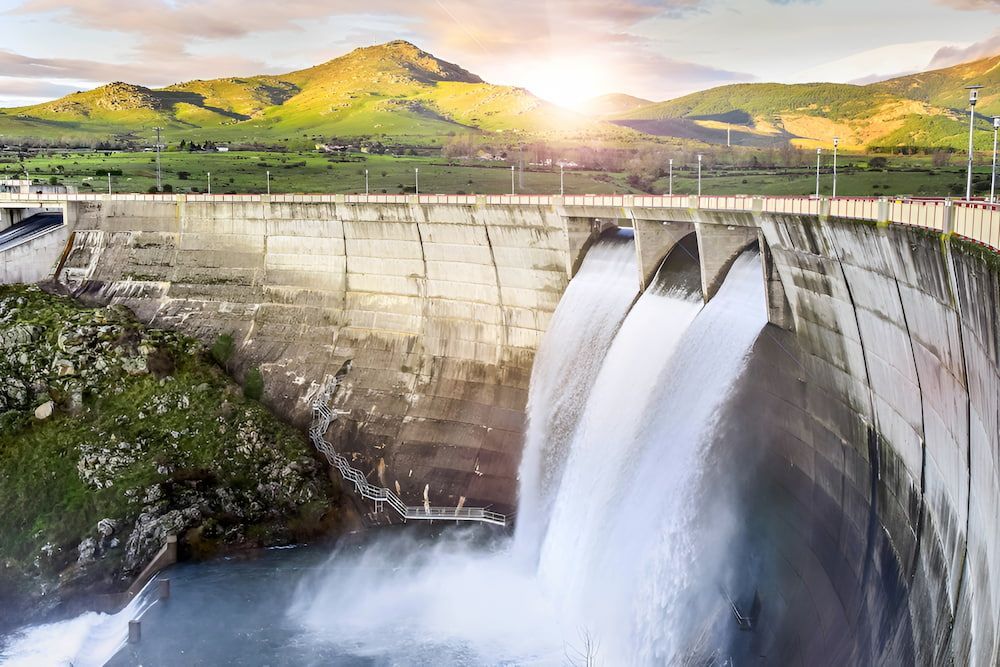 A Waterfall Is Coming Down A Dam With Mountains — Wilsons Excavations & Plant Hire in Myocum, NSW