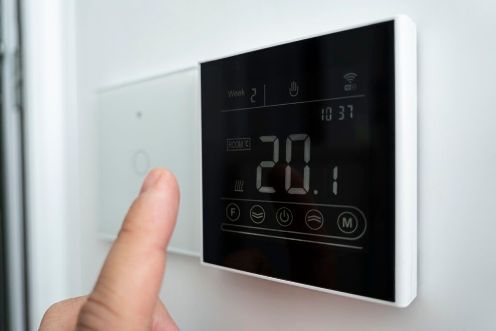 Discover the HVAC Myth: Closing Vents Won't Save Energy 9 Hand touching a digital thermostat showing a temperature of 20.1 degrees Celsius.