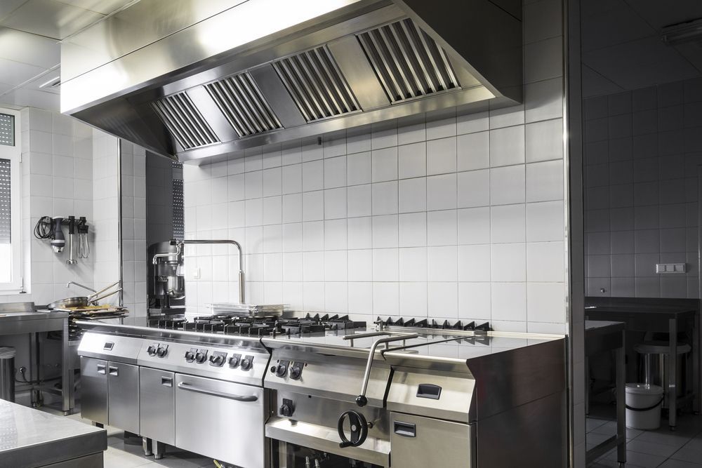 Commercial kitchen with stainless steel stove, range hood, and tiled backsplash