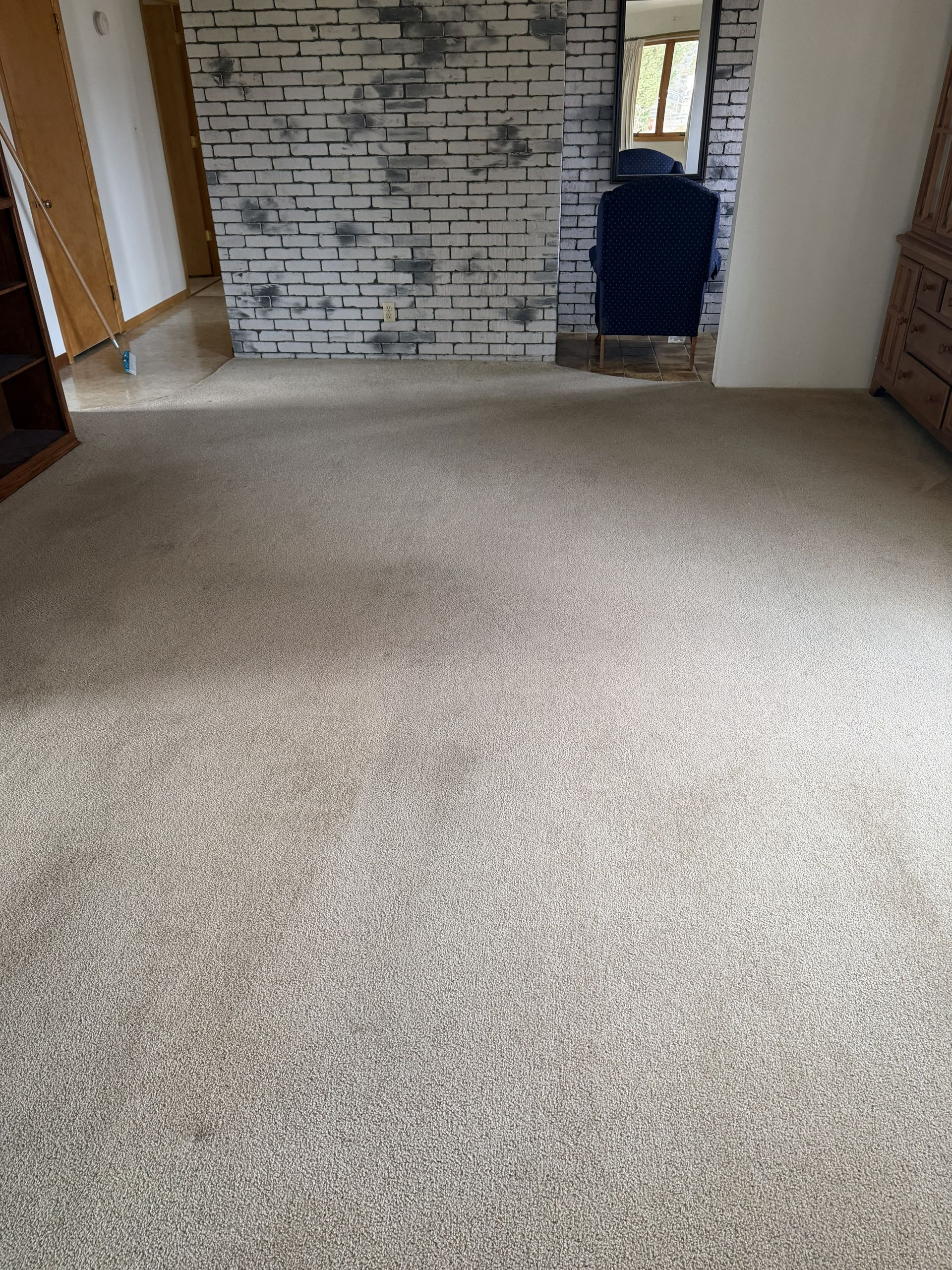 Carpeted living room with a brick fireplace and doorway in the background
