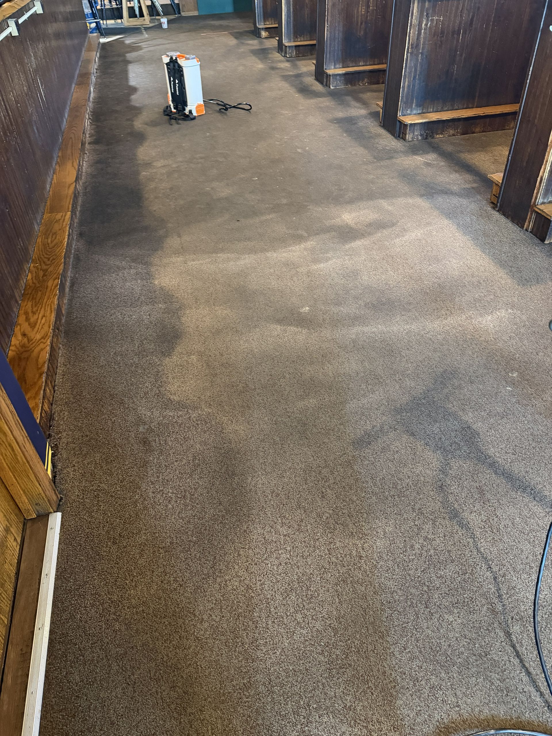 Carpeted hallway with a small cleaning machine near the far end and wood-paneled walls on both sides